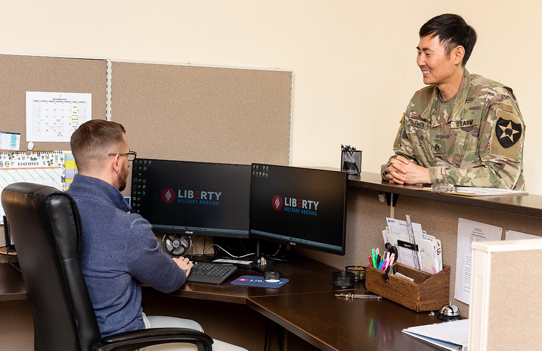 Man working at a desk talking to a soldier