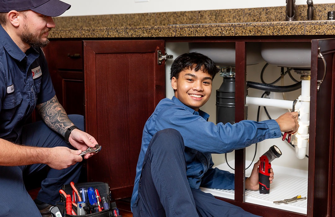 Person fixing a pipe under the sink 