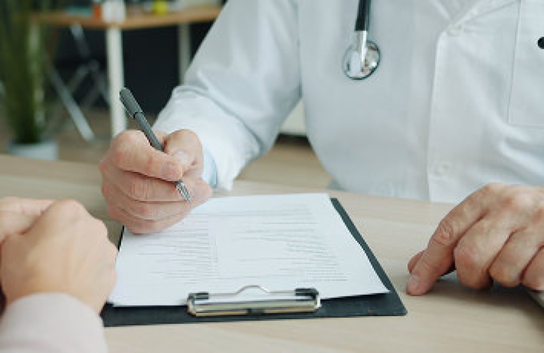 Doctor filling out a patient form on a clipboard.