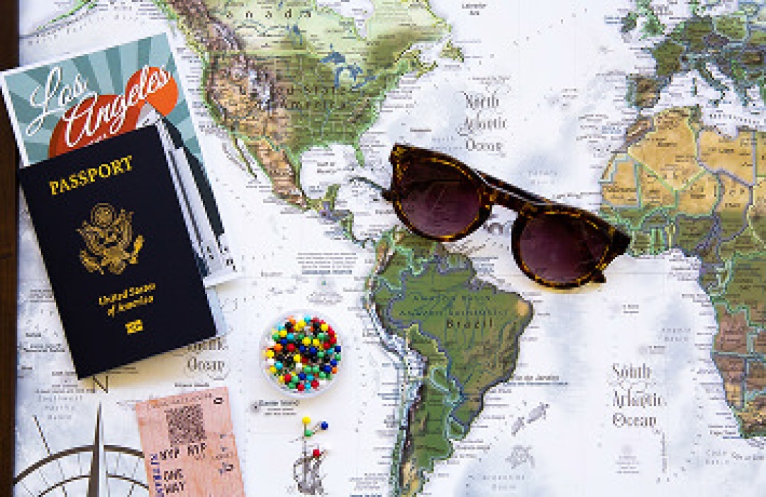 US passport and sunglasses laid out on a world map.