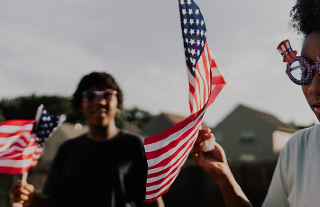 People waving American flags outdoors.