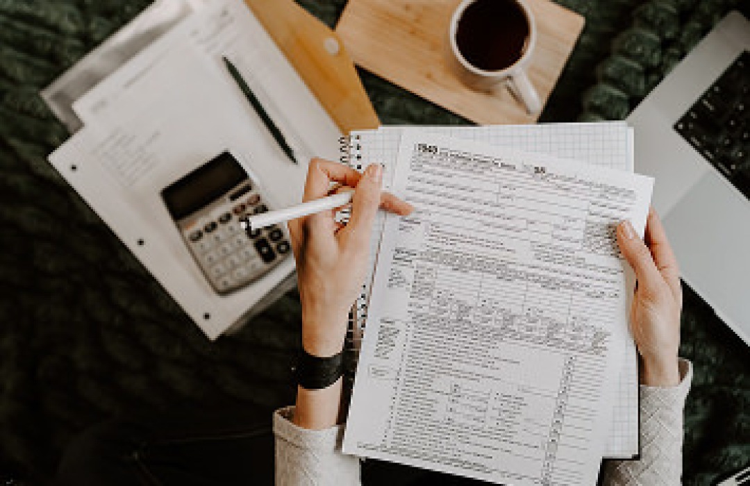 Person reviewing and filling out tax forms at a desk.
