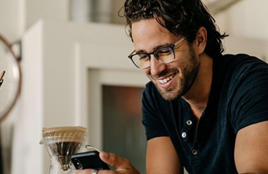 Man smiling while looking at his smartphone.