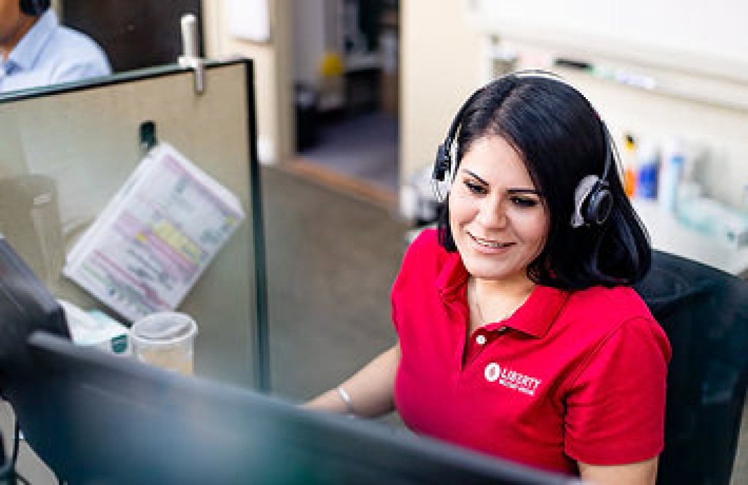 Customer support representative wearing a headset at her computer desk.