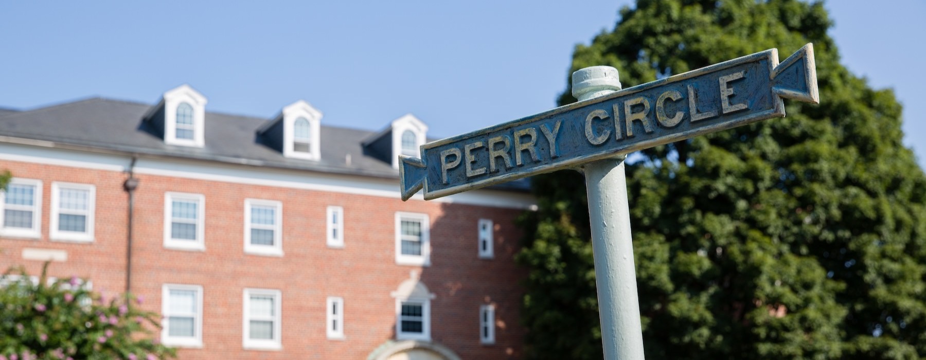 a street sign with a brick building and trees in the background
