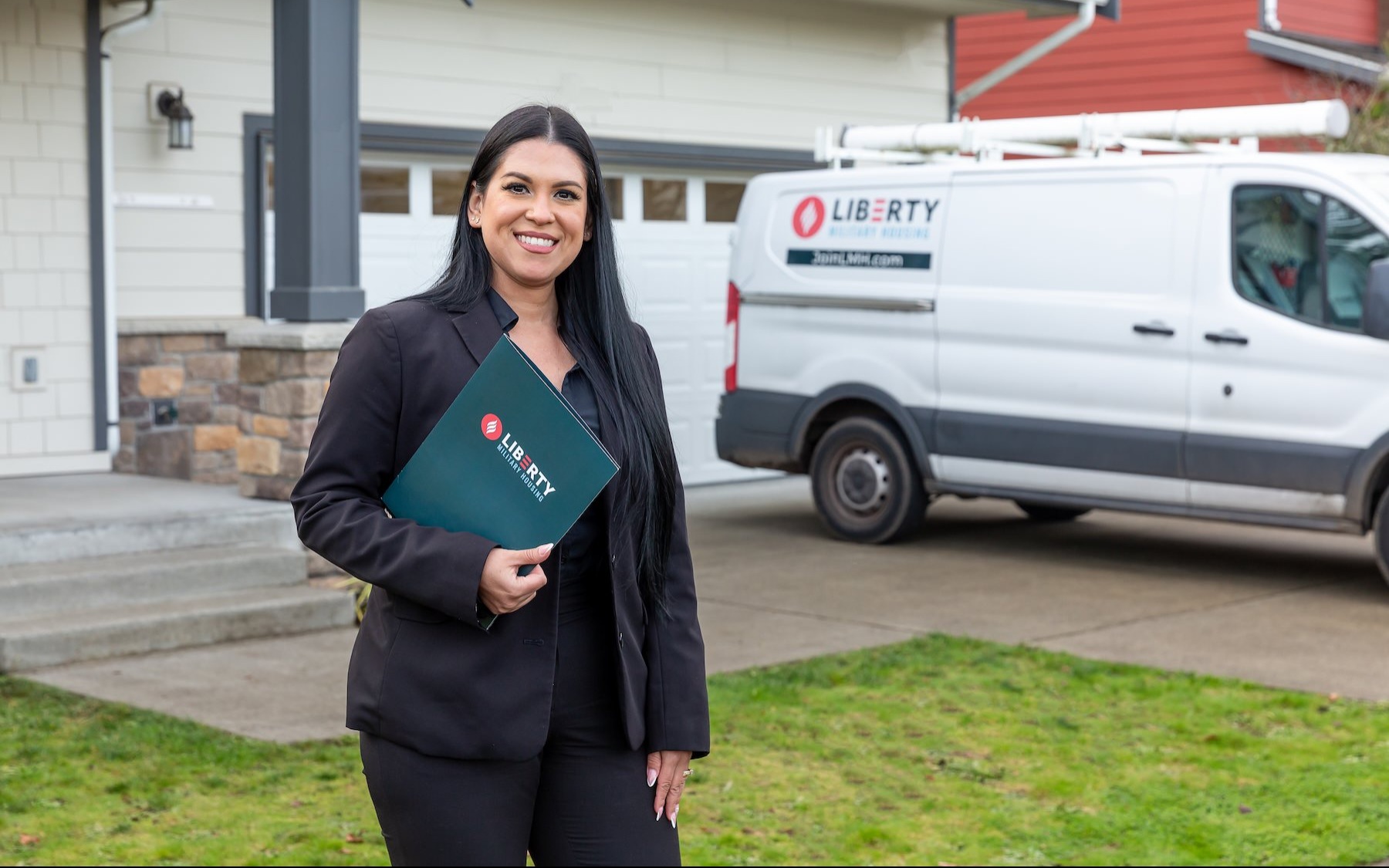 a woman holding a folder in front of a house