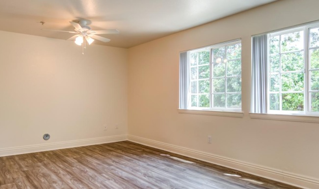 a room with a wood floor and a ceiling fan and a window
