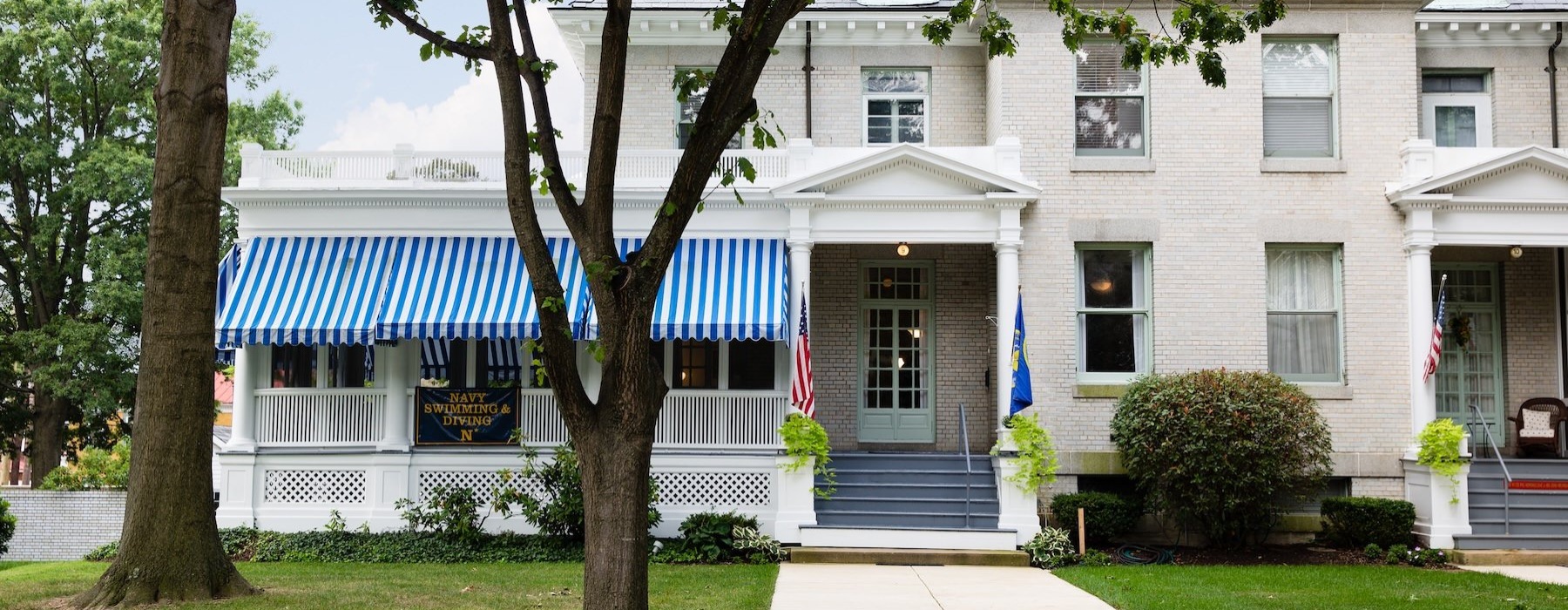 a house with a staircase leading to a front door and a front yard with trees