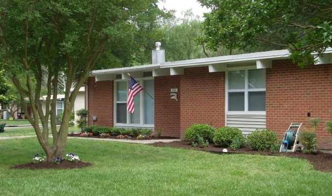 a brick home with grass and an American flag