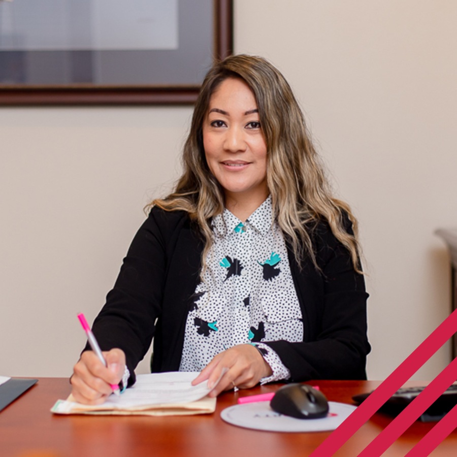 woman sitting at desk smiling with pen and paper