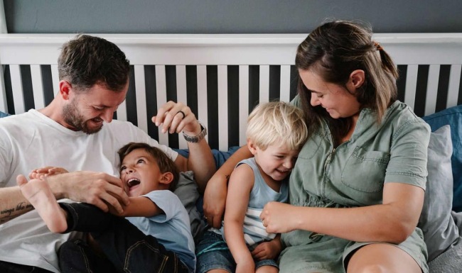 parents play with their children on a bed