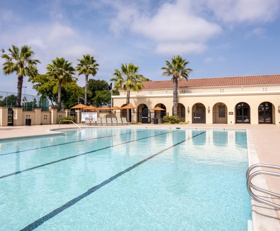 a swimming pool in front of a building with palm trees