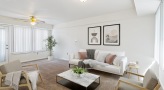 living room with couch, two chairs, and coffee table.  Tall plant in back corner, two pieces of art on wall