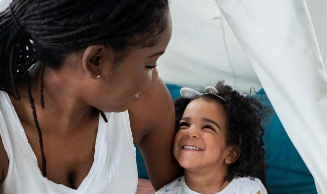mother sits with her daughter in an indoor tent