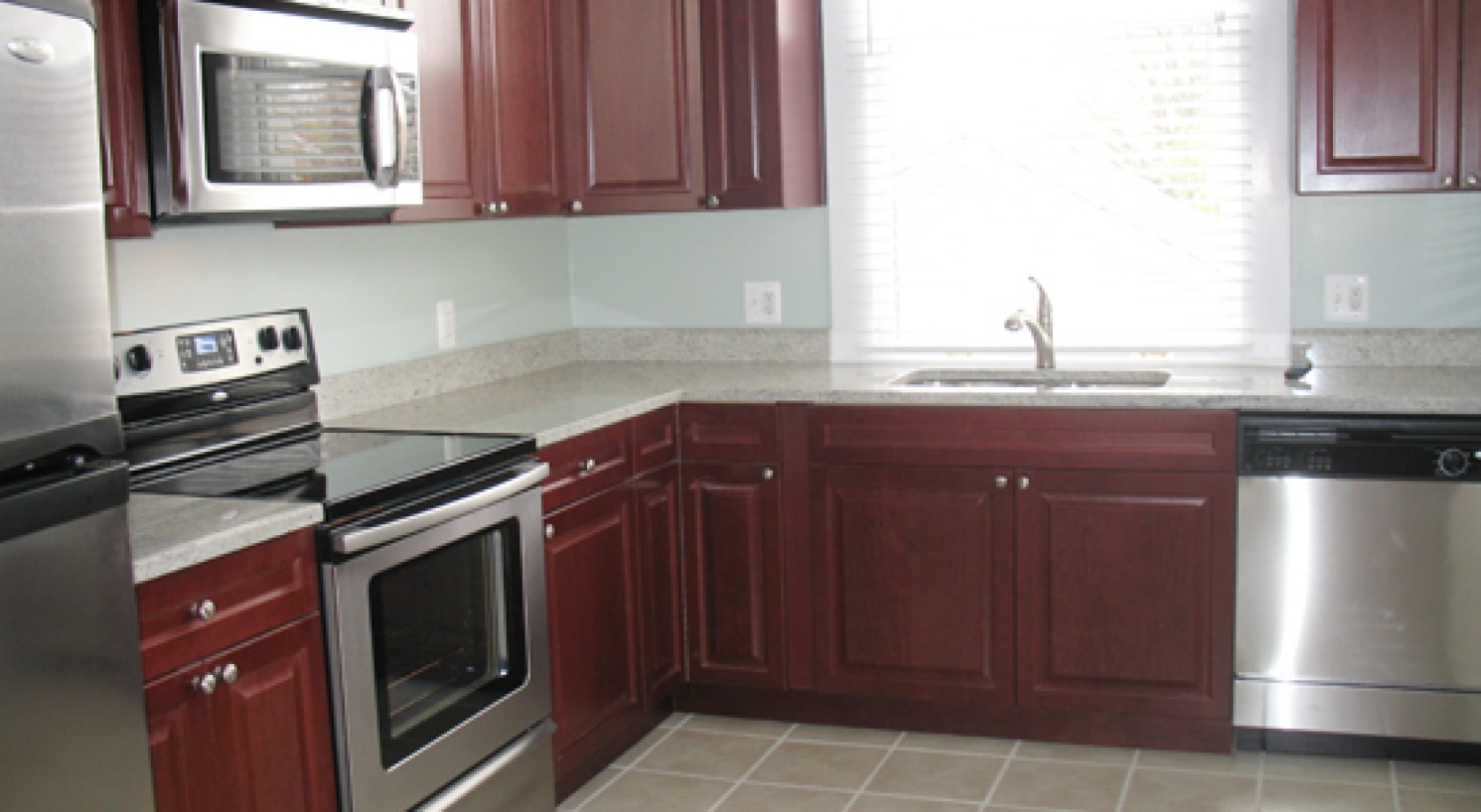 kitchen with cherry cabinets and stainless steel appliances to include dishwasher microwave stove and fridge