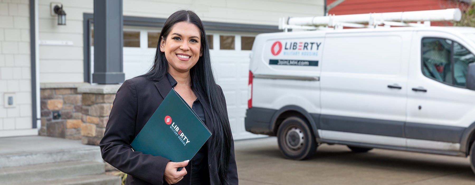 a person holding a folder with a van and house in the background