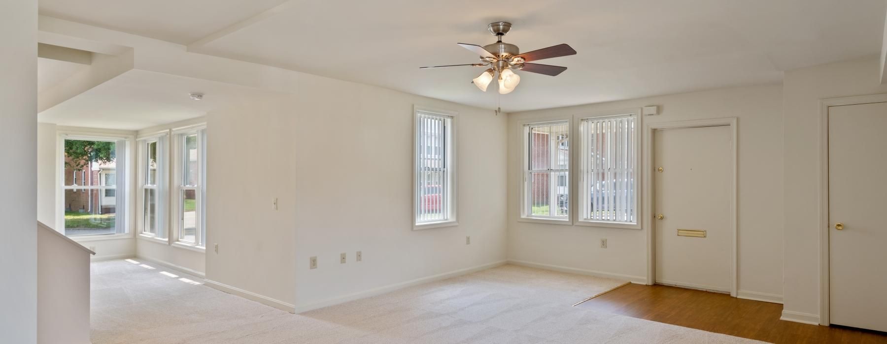 a large empty room with a ceiling fan and a carpet