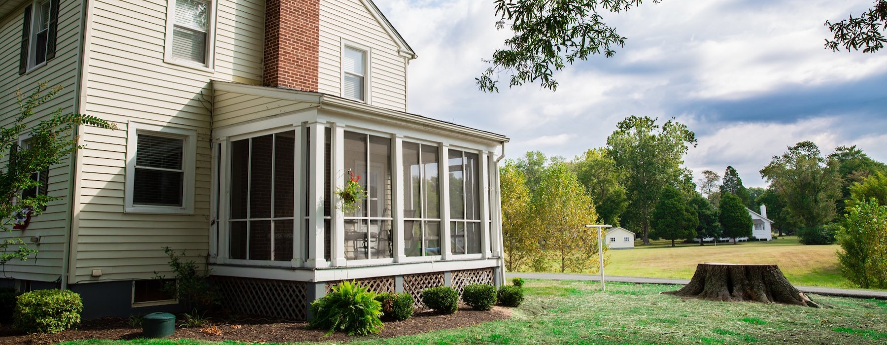a white home with grass and a tree stump in front of it