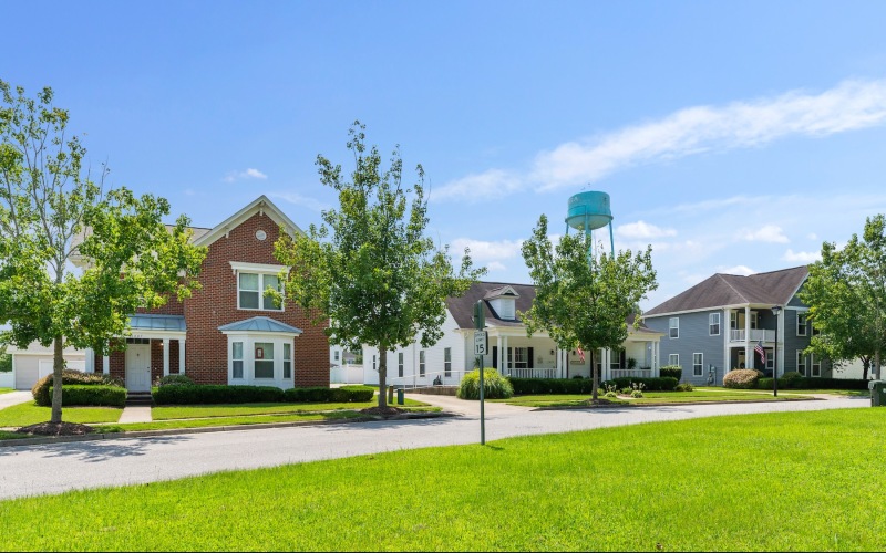 a row of houses with green yards and trees