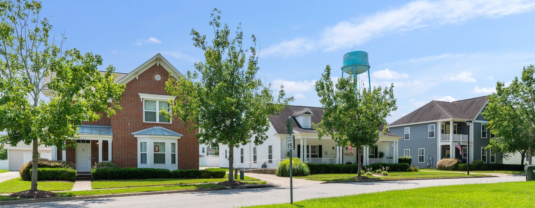 a row of houses with a green lawn and a water tower