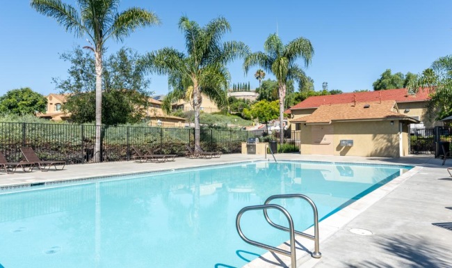 a swimming pool with trees and a fence around it