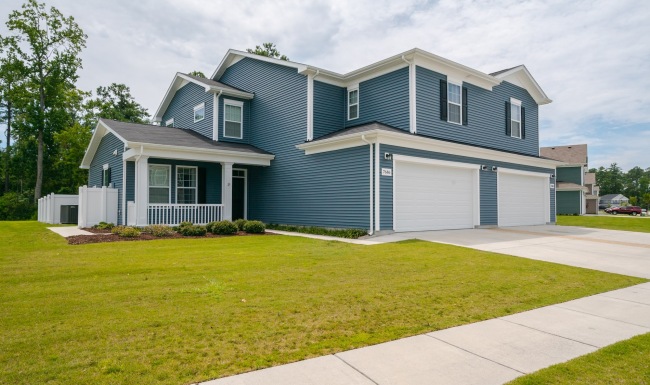 a blue house with garage porch and grass yard