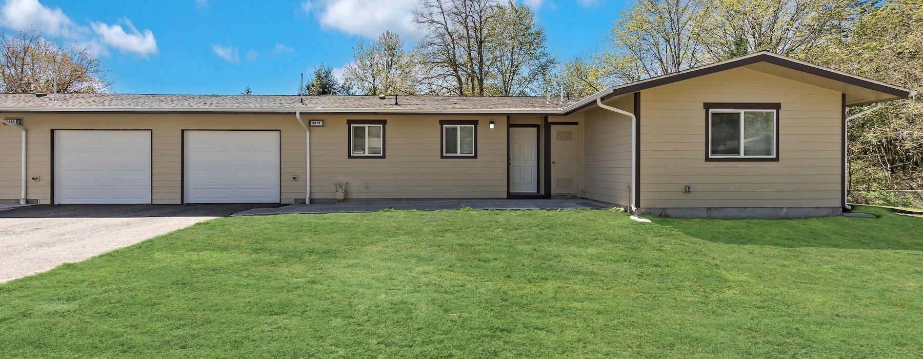 a house with a driveway and trees in the back