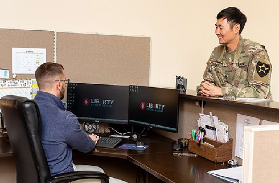 Military member talking to a housing office employee at a front desk.