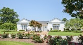 a white house with a lawn and trees in front of it
