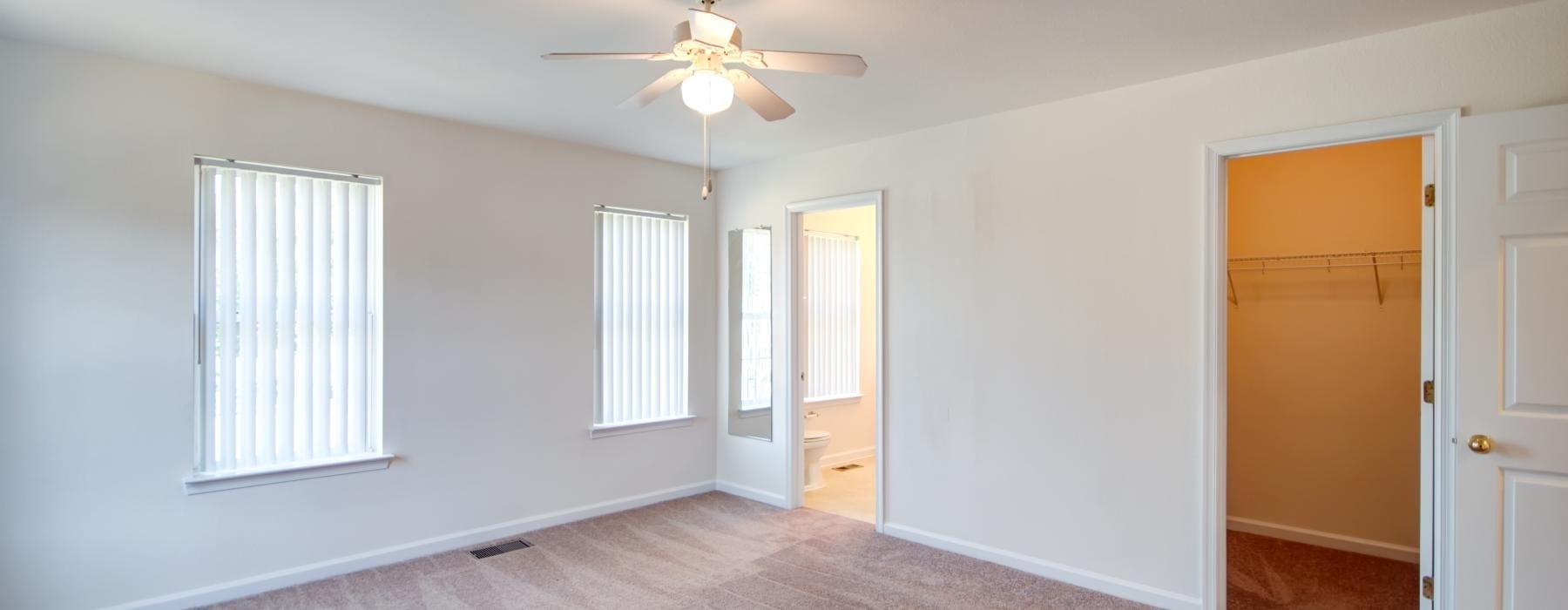 a room with a ceiling fan and a carpet