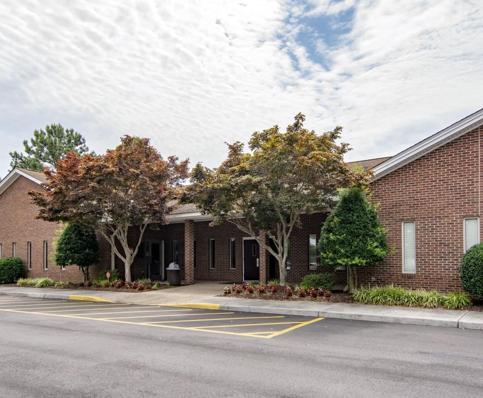 a brick building with trees and a parking lot