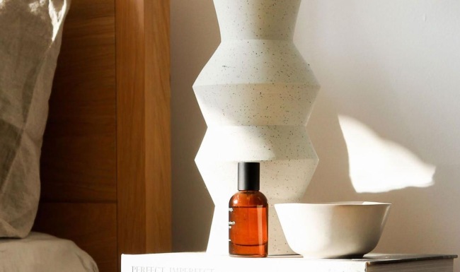 a vase with cotton stems on a bedside table