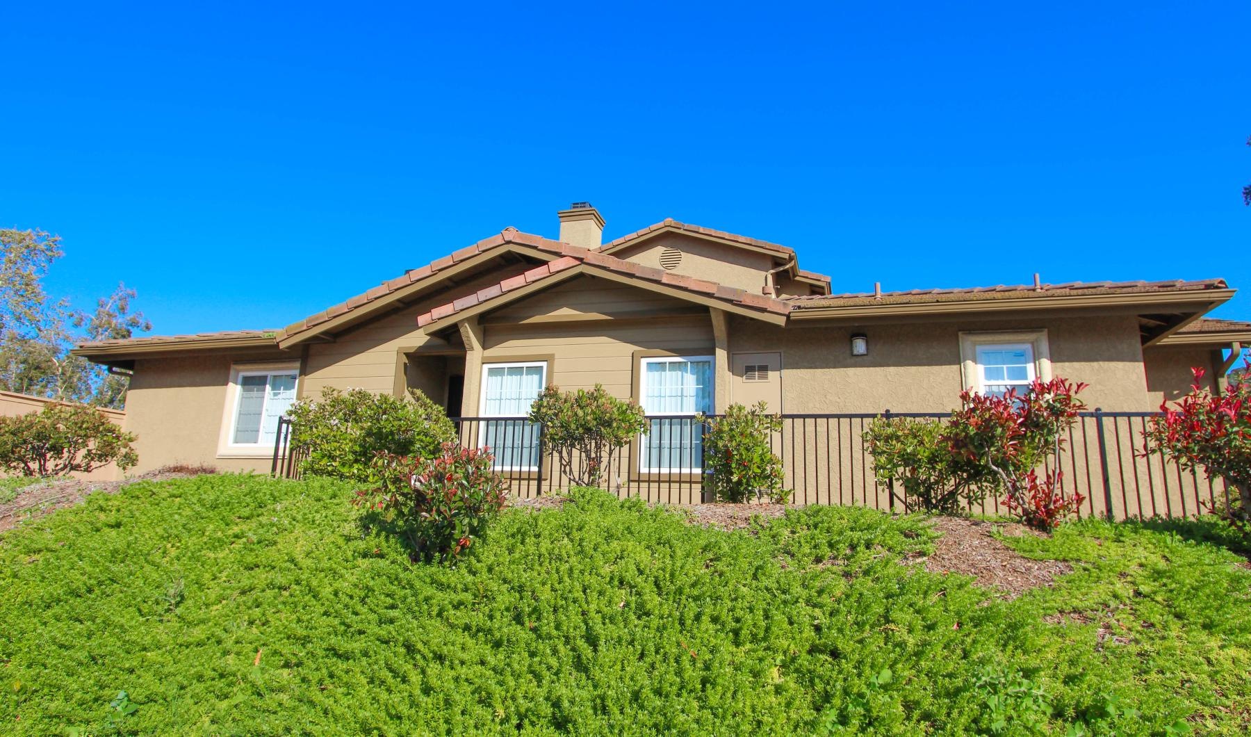 a house with a fence and bushes in front of it