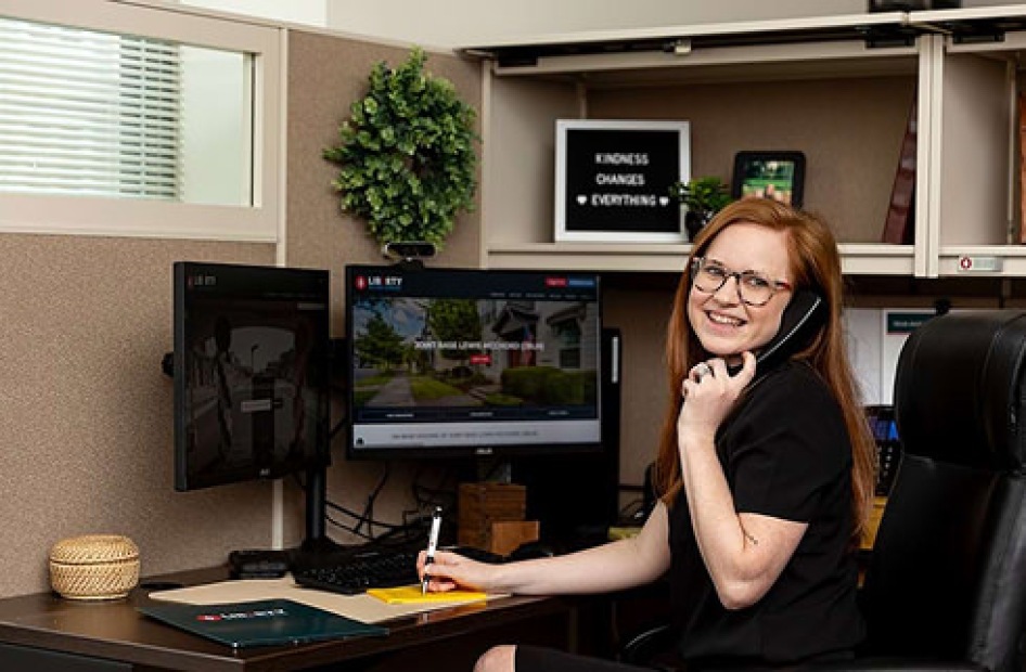 Office worker talking on the phone while writing notes at her desk.