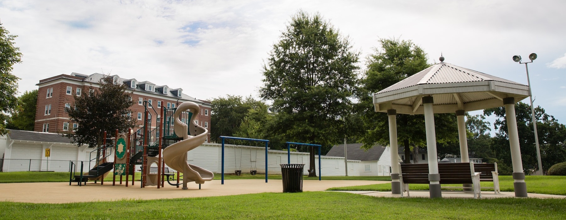 a playground with a slide and a gazebo with a bench