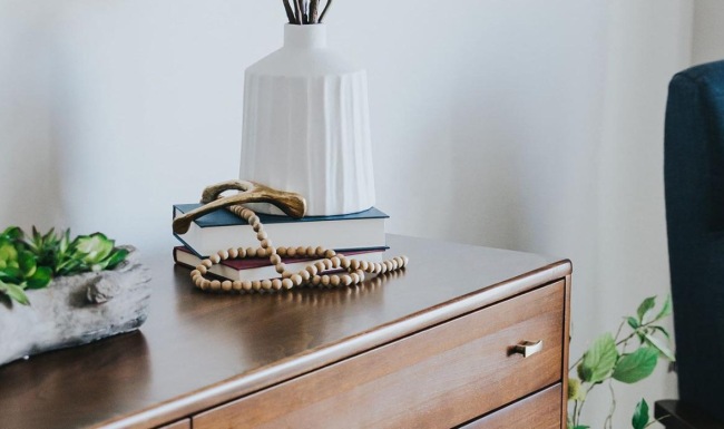 a dresser with a vase of plants on top