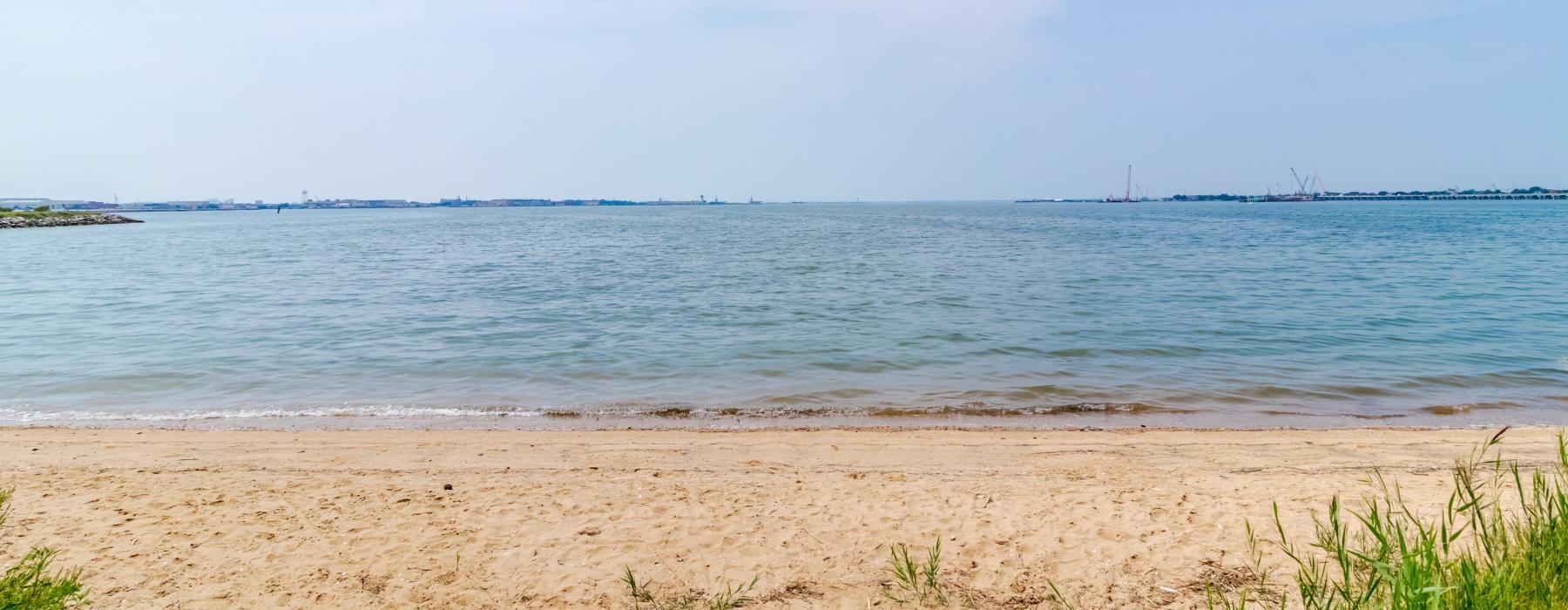 a sandy beach with water and land in the distance