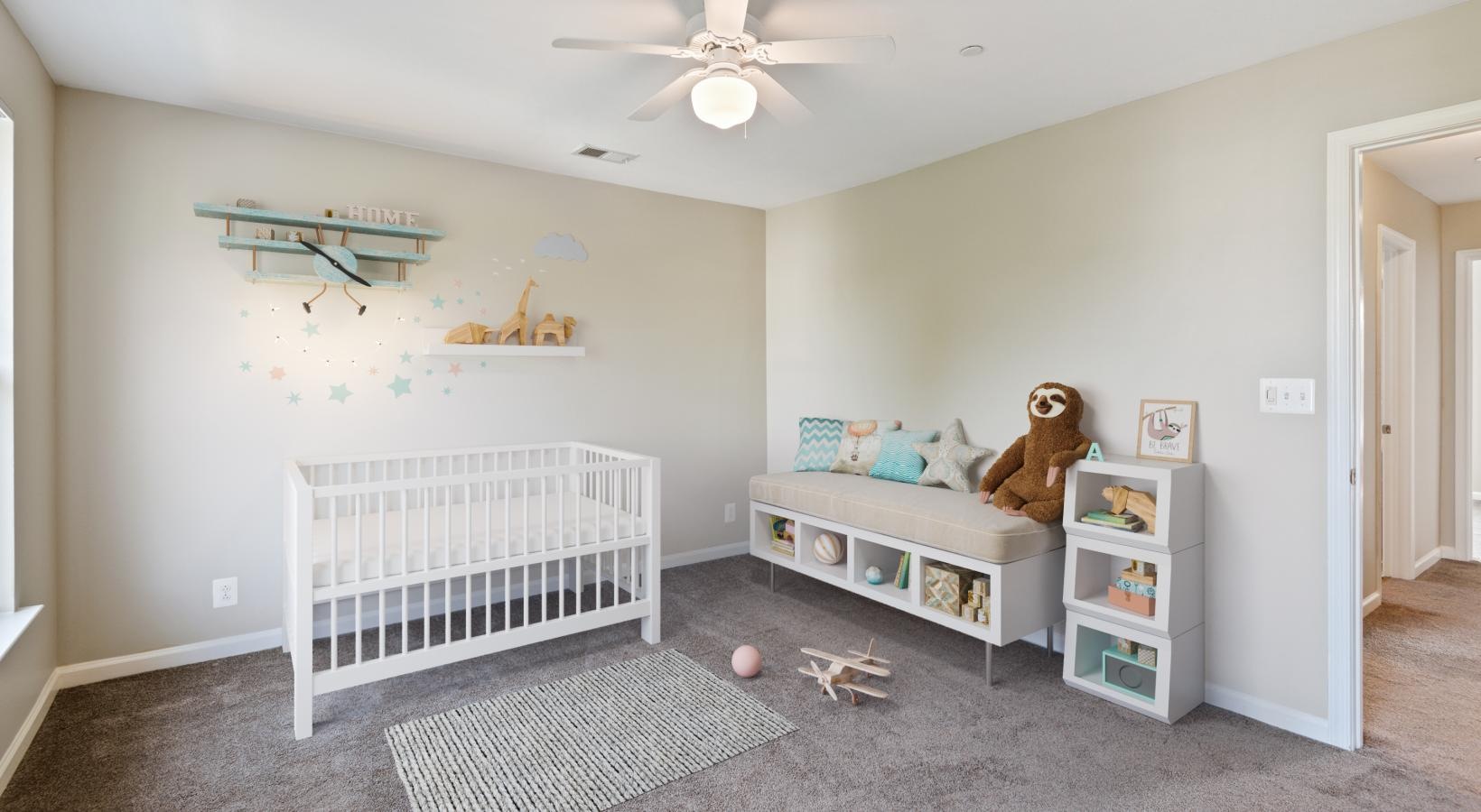 a room with a crib and a ceiling fan