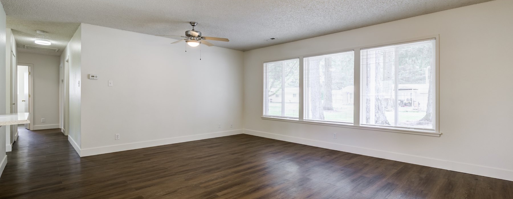 a room with white walls, large windows and wood-style flooring