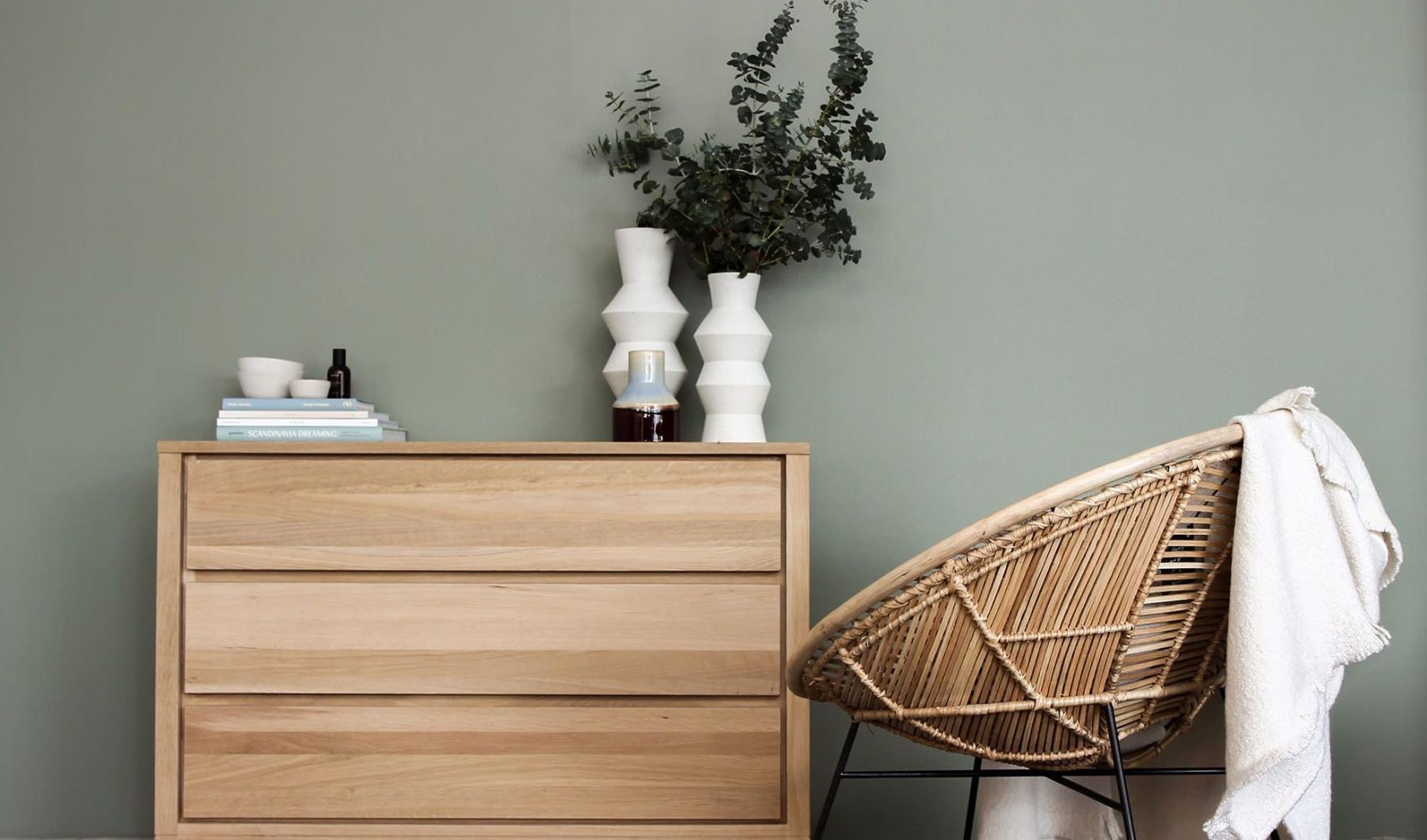 decor on a tall, wooden dresser next to a papasan chair with a throw