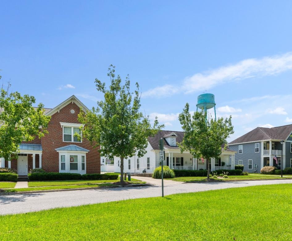 a row of houses with a road in front of it and grass