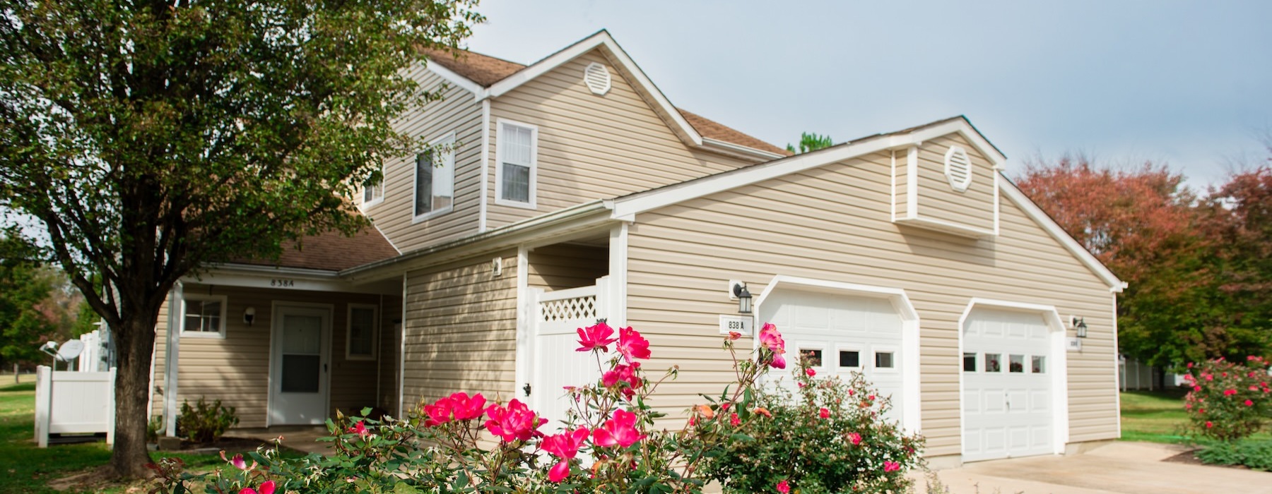 a house with a garage and flowers in front of it