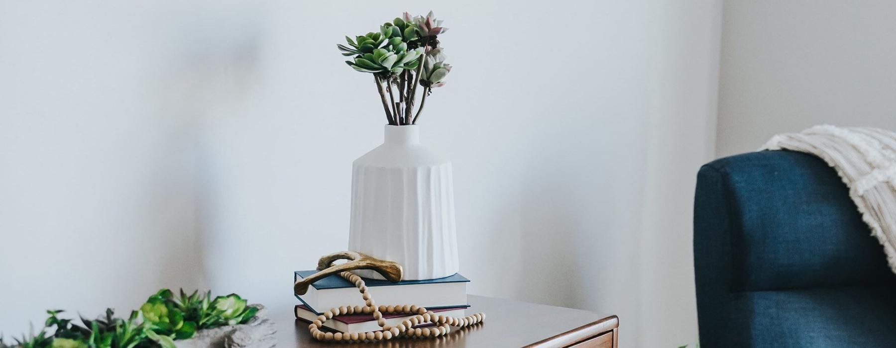 a dresser with a vase of plants on top